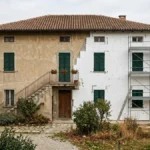 Casa colonica nella pianura romagnola con metà facciata già rivestita dai pannelli del cappotto termico, immagine illustrativa